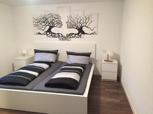 2 camas en una habitación blanca con árboles en la pared en Casa Perla Bianca, en Rheinfelden