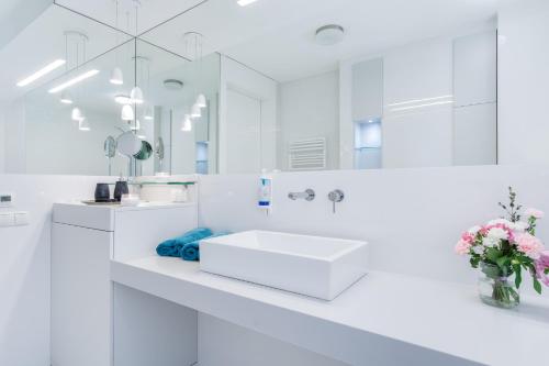 a white bathroom with a sink and a mirror at Elite Apartments Prestige Old Town in Gdańsk