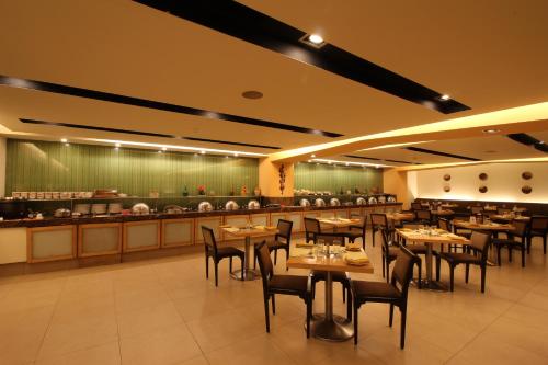 a dining room with tables and chairs and a kitchen at Minerva Grand Secunderabad in Hyderabad