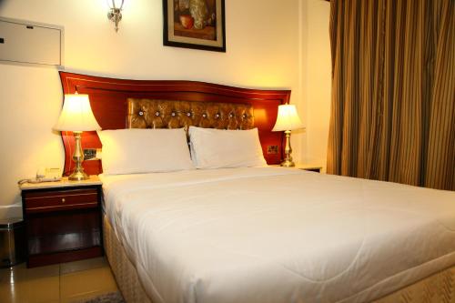 a large bed in a hotel room with two lamps at Saffron Hotel in Dubai