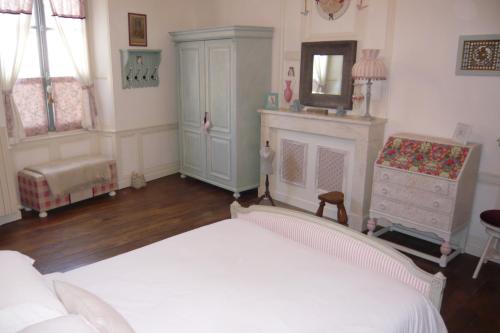a bedroom with a white bed and a fireplace at L'Arbre D'Ange in Montmorillon