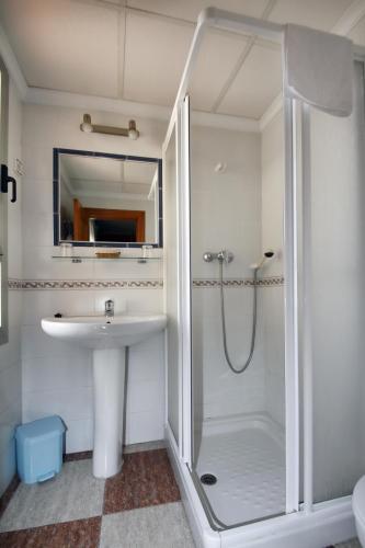 un bagno bianco con doccia e lavandino di Hotel Sevilla a Almería