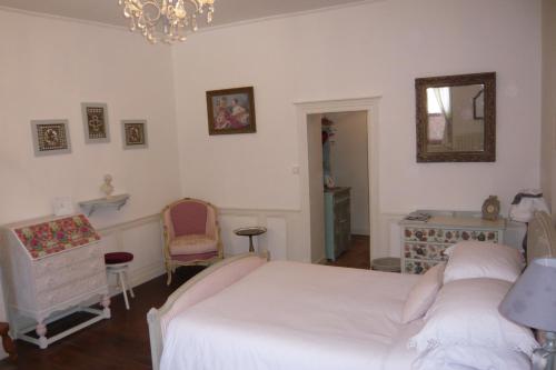 a bedroom with a bed and a chair and a mirror at L'Arbre D'Ange in Montmorillon