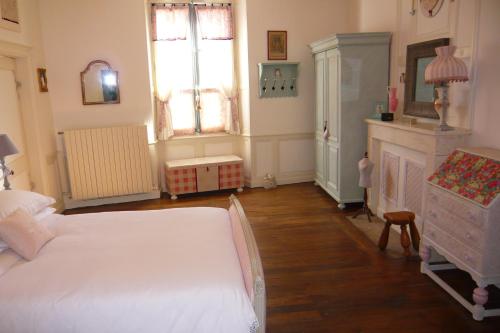 a bedroom with a large white bed and a fireplace at L'Arbre D'Ange in Montmorillon