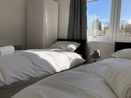 2 camas blancas en una habitación con ventana en Glenrothes Central Apartments - One bedroom Apartment, en Glenrothes