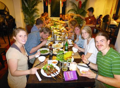 Eine Gruppe von Menschen, die an einem Tisch sitzen und Essen essen. in der Unterkunft Rainbow Safari Resort in Sauraha