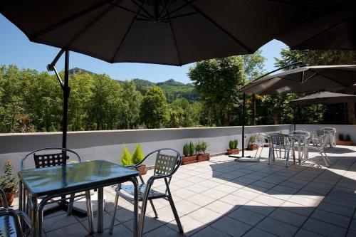 a patio with tables and chairs and an umbrella at Hotel Balneario Areatza Nº 01224 in Areatza
