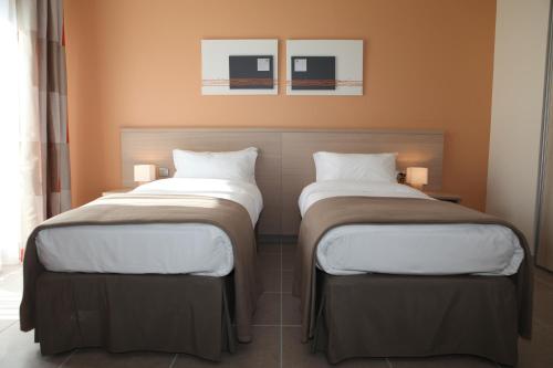 two beds sitting next to each other in a room at The Originals Boutique, Hotel l'Occitan, Aubagne in La Destrousse
