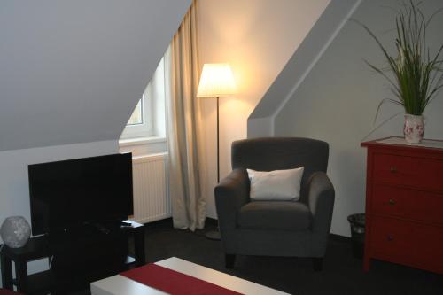 a living room with a chair and a television at Landhaus Elbeflair bei Dömitz in Lenzerwische