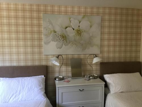 a bedroom with two beds and a nightstand with two lamps at Ingleneuk Bed and Breakfast in Edinburgh