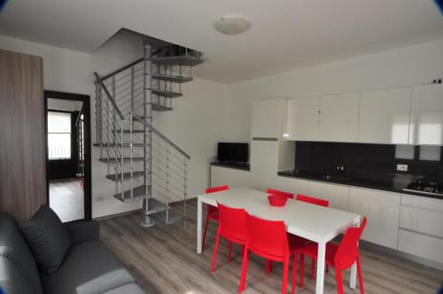 une cuisine et une salle à manger avec une table blanche et des chaises rouges dans l'établissement North Wind Camping & Apartment, à Domaso