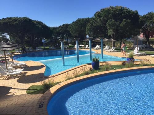 a large swimming pool with chairs and umbrellas at a resort at Apartamento Praia da Oura in Albufeira