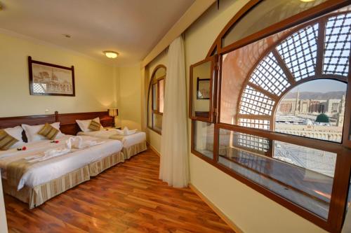 a hotel room with two beds and a large window at Manazeli Madinah in Medina
