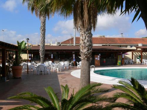 a resort with a swimming pool and chairs and palm trees at Destinos De Sol Los Alcazares - Montepío Minería in Los Alcázares