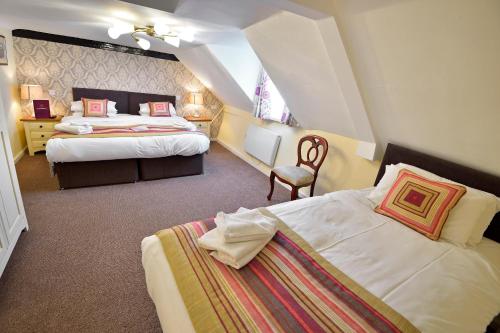 a hotel room with two beds and a chair at The Royal Victoria and Bull Hotel in Dartford