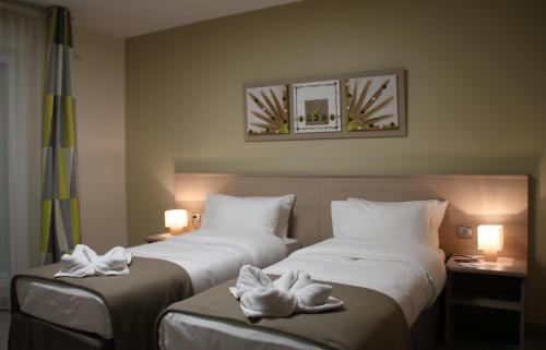 two beds in a hotel room with towels on them at The Originals Boutique, Hotel l'Occitan, Aubagne in La Destrousse