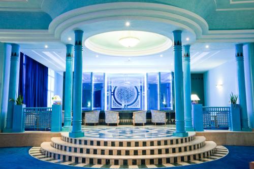 a lobby with blue columns and a table and chairs at El Mouradi Mahdia in Mahdia