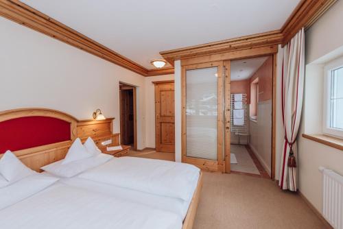 a bedroom with a large white bed and a window at Hotel Ennstalerhof in Ramsau am Dachstein