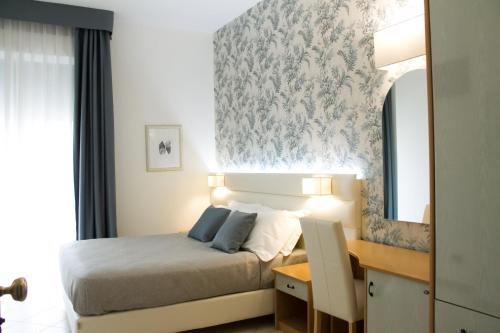 a bedroom with a bed and a desk and a mirror at Hotel La Conchiglia in Bellaria-Igea Marina