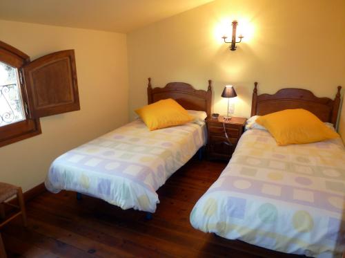 a bedroom with two beds and a lamp and a window at Can Mahola in Beuda