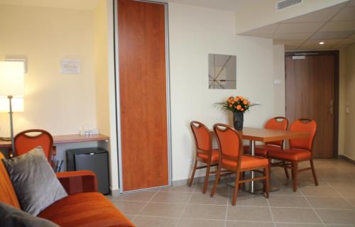 a dining room with a table and orange chairs at The Originals Boutique, Hotel l'Occitan, Aubagne in La Destrousse