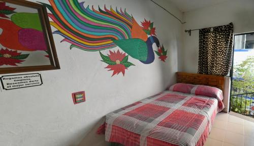 a bedroom with a bed and a painting on the wall at Posada Joan Sebastian in Taxco de Alarcón