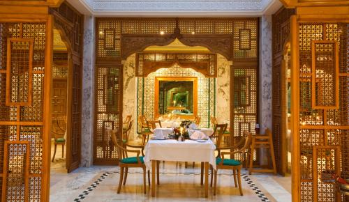 a dining room with a table and chairs and a mirror at El Mouradi Mahdia in Mahdia