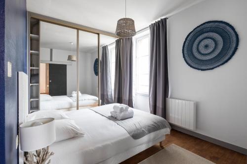 une chambre avec un lit blanc et un grand miroir dans l'établissement L'Aviron by Cocoonr, à Saint-Malo