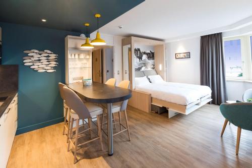サン・マロにあるRésidence Neptuniaのベッド、テーブル、椅子が備わるホテルルームです。