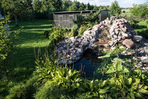 a garden with a pond and a rock wall at Siedlisko Sabinowo in Węgorzewo