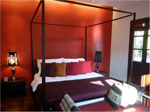 a bedroom with a canopy bed with red walls at Luang Prabang Nagara Villa River View in Luang Prabang