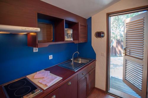 Elle comprend une petite cuisine avec un évier et une fenêtre. dans l'établissement Résidence Mobydick, à Porto-Vecchio