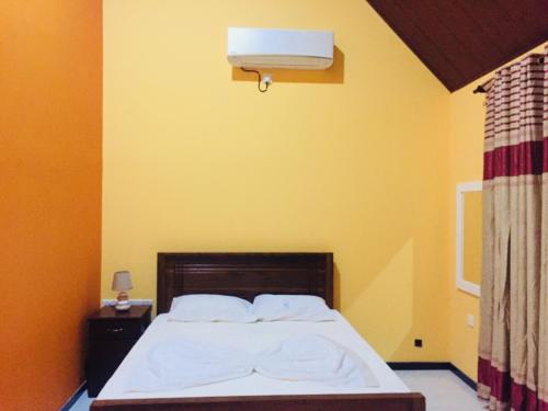 a bedroom with a bed and a yellow wall at Crown Holiday Village near Marawila in Nattandiya