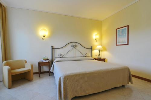 a bedroom with a large bed and a chair at Hotel Airone isola d'Elba in Portoferraio