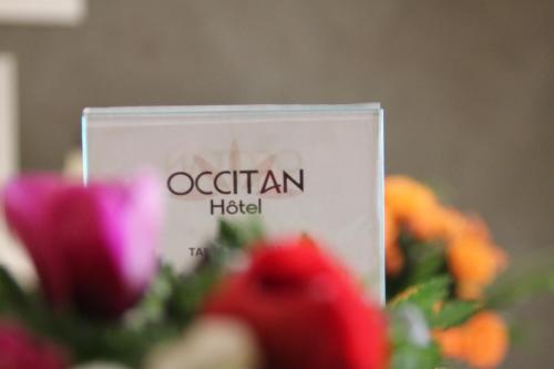 a sign in front of a bunch of flowers at The Originals Boutique, Hotel l'Occitan, Aubagne in La Destrousse