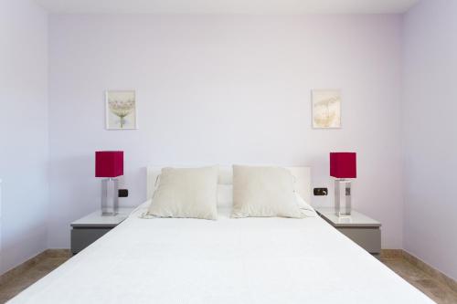 een slaapkamer met een wit bed en 2 lampen bij El Ancla in Los Cristianos