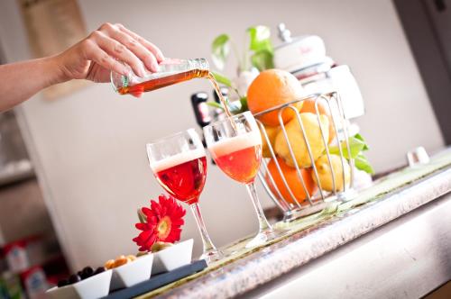 a person pouring wine into two glasses on a counter at Hotel Milan in Rosolina Mare