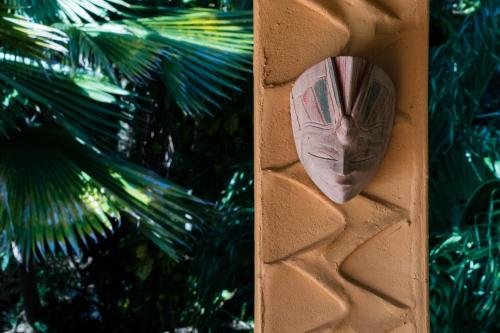 a mask on a wall next to a palm tree at Reef View Pavilions - Villas & Condos in Lance aux Épines