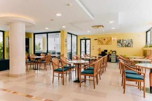 a restaurant with tables and chairs and windows at Hotel Villa Claudia in Bellaria-Igea Marina