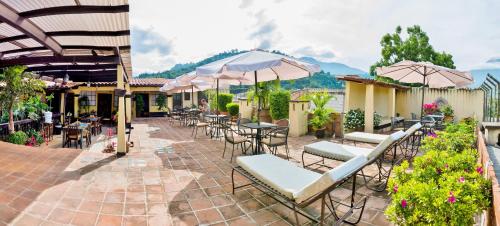 an outdoor patio with tables and chairs and umbrellas at Hotel Las Camelias Inn by AHS in Antigua Guatemala