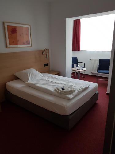 a hotel room with a bed with white sheets at Hotel Haus vom Guten Hirten in Münster