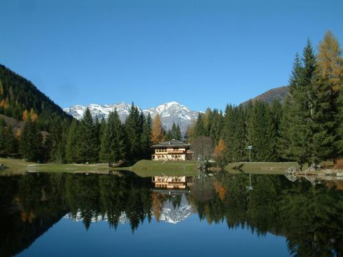 a reflection of a house in a lake with mountains at Residence Ca' Delle Margherite in Pellizzano
