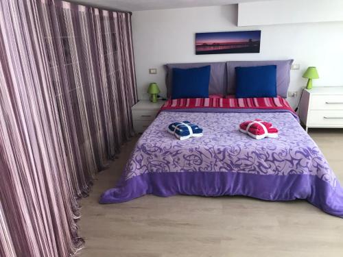 - une chambre dotée d'un lit violet avec deux chapeaux dans l'établissement Loft delizioso, à Cagliari