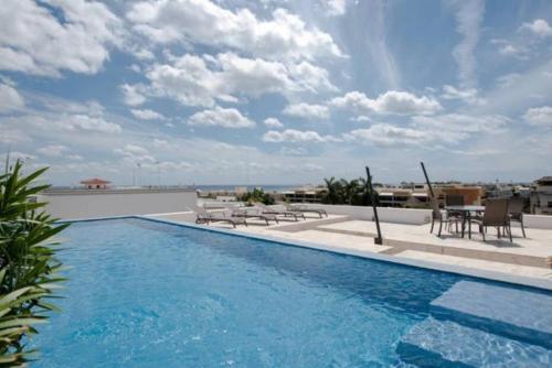 a swimming pool with chairs and tables on a building at Infinito by Zamá Homes in Playa del Carmen
