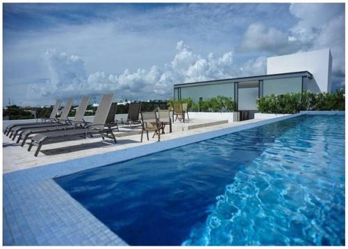 a swimming pool with chairs and a building at Infinito by Zamá Homes in Playa del Carmen