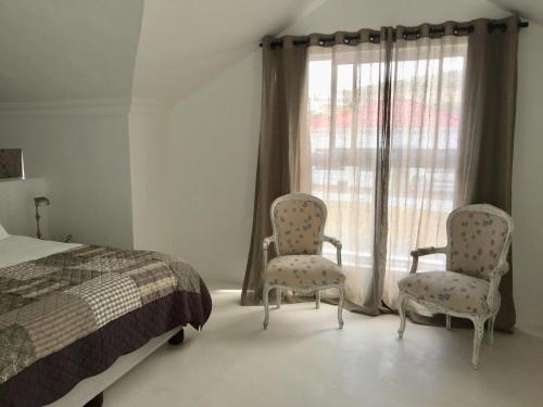 1 dormitorio con 2 sillas, 1 cama y 1 ventana en D’Hub guest cottage, en Agulhas