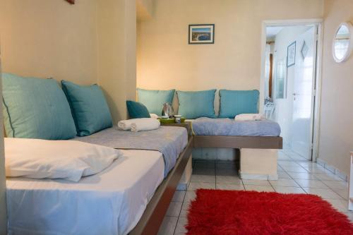 a bedroom with two beds with blue pillows and a red rug at Stathopoulos Apartments in Sampatiki