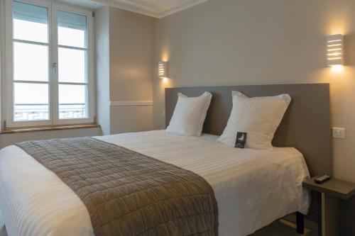 a bedroom with a large bed with white sheets and pillows at Hotel Jean Moët in Épernay