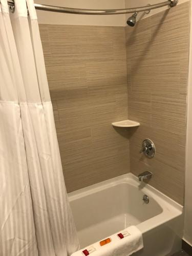 W łazience znajduje się wanna z zasłoną prysznicową. w obiekcie Baymont Inn and Suites by Wyndham Columbus / Near OSU w mieście Columbus