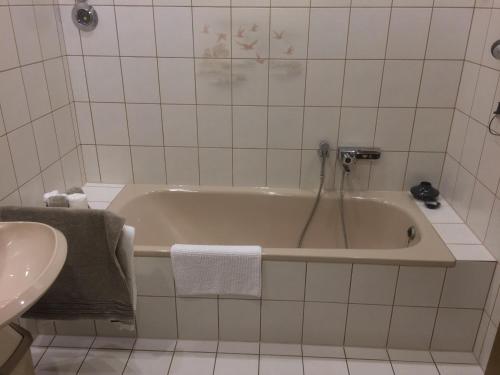 a white bathroom with a tub and a sink at Ferienwohnung Bachem in Hürtgenwald